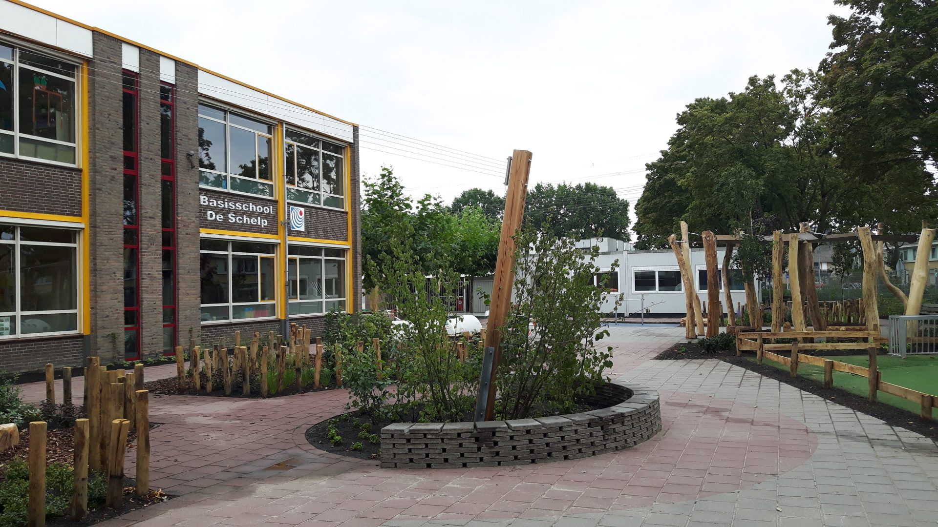 Groen schoolplein met paaltjes en draden voor klimgroen.