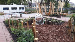 Speeltoestellen geïntegreerd in groen schoolplein.