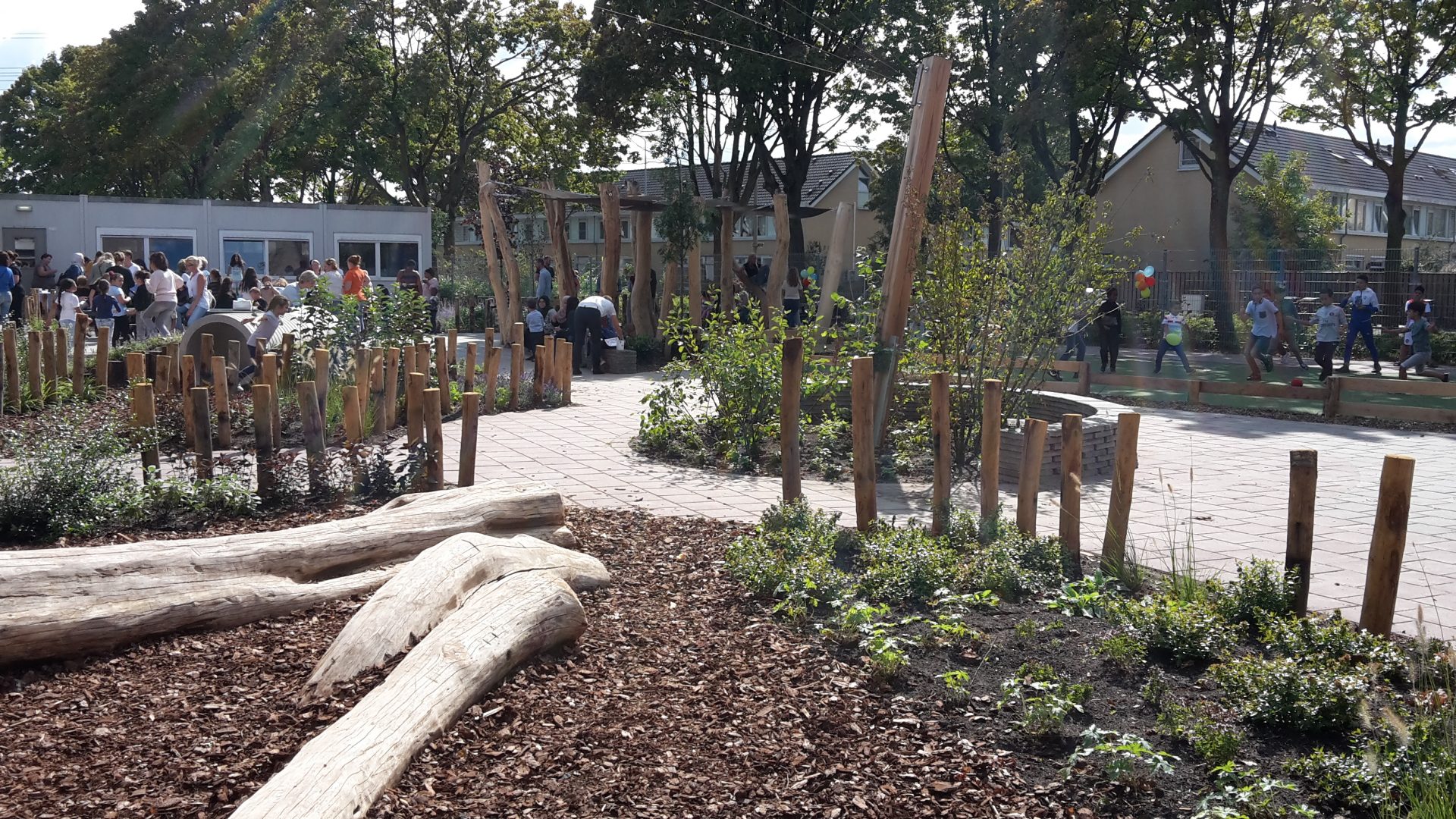 Speeltoestellen geïntegreerd in groen schoolplein.