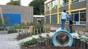 Speeltoestellen geïntegreerd in groen schoolplein.