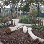 Speeltoestellen geïntegreerd in groen schoolplein.