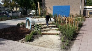 Speeltoestellen geïntegreerd in groen schoolplein.